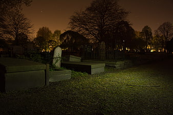 Dark Cemetery at Night with Tombstones and Bare Trees