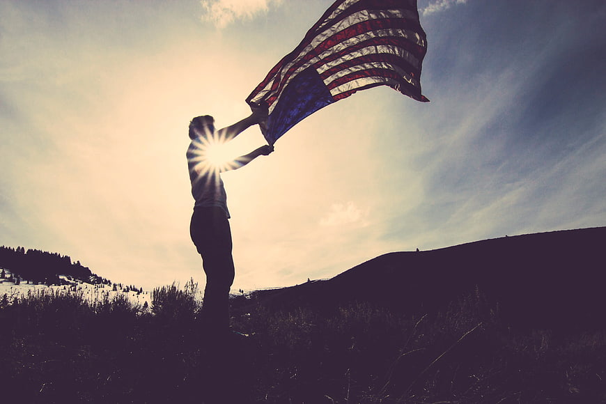 Silhouette of Man Holding American Flag on Hilltop