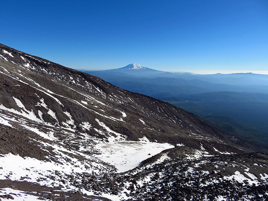 Snowy Mountain Slope with Distant Volcano Peak