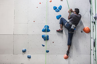 Man rock climbing on indoor wall with blue and orange holds
