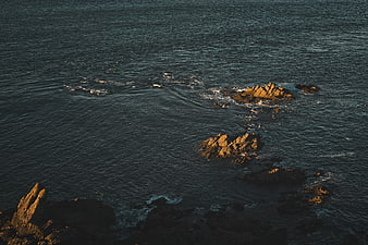 Aerial View of Rocky Outcrops in Dark Ocean Waters