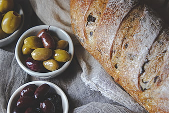 Rustic sourdough bread loaf with bowls of green and black olives