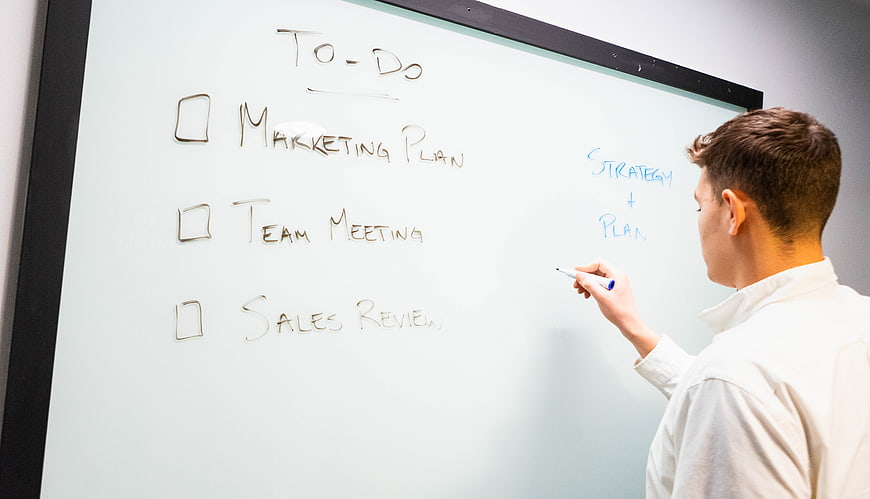 Man Writing To-Do List on Whiteboard in Office