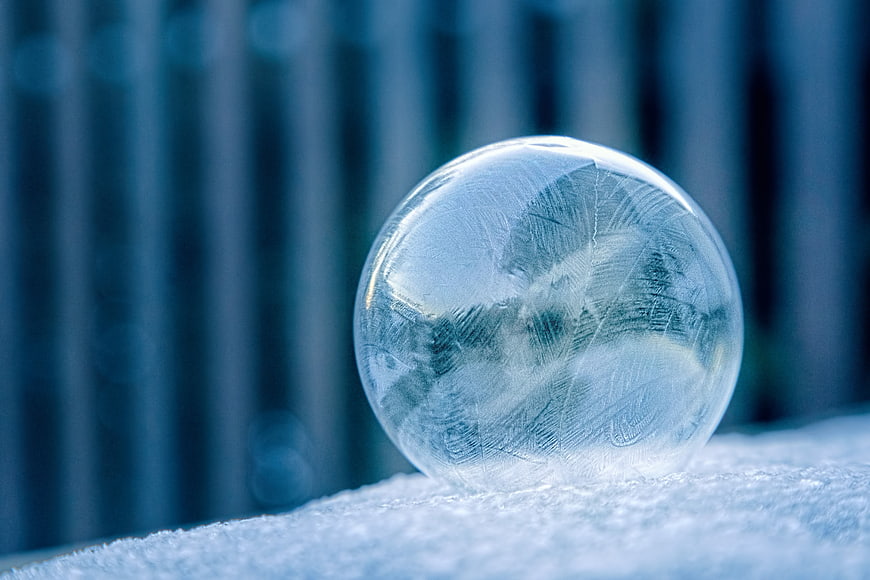 Frosted Ice Sphere on Snowy Surface with Blue Bokeh Background