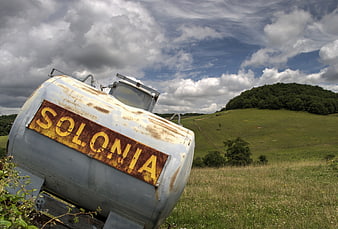 Rusty Solonia Water Tank in Green Meadow Landscape