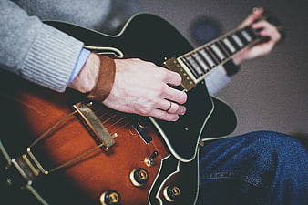 Close-up of hands playing a sunburst electric guitar