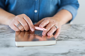 Woman writing in a rose gold notebook with a pink pen