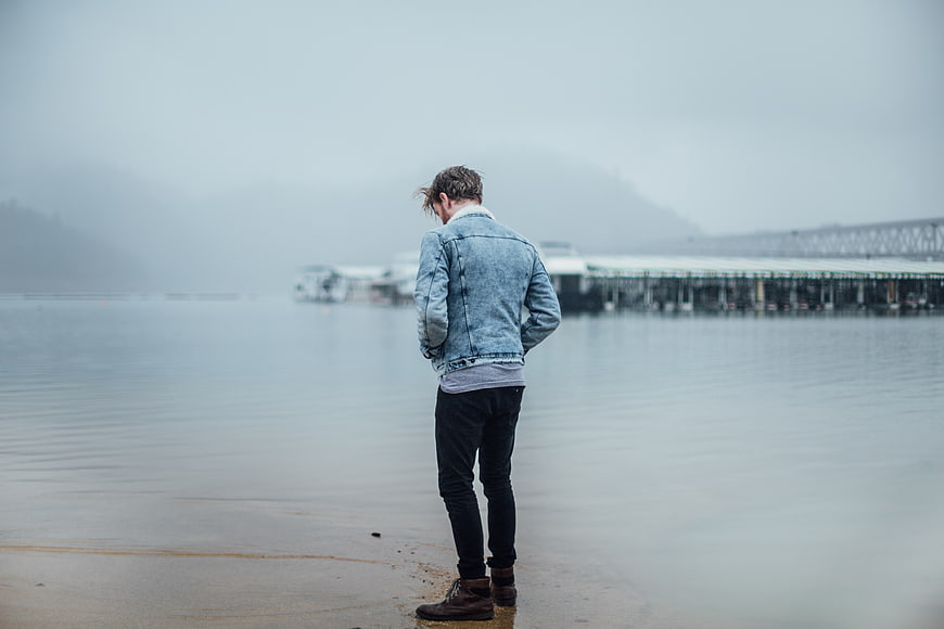 Man in Denim Jacket Standing by Foggy Lake