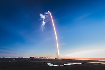 Rocket Launch Light Trail at Dusk Over Desert Landscape