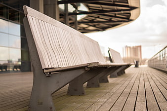 Modern wooden bench on urban deck with city background