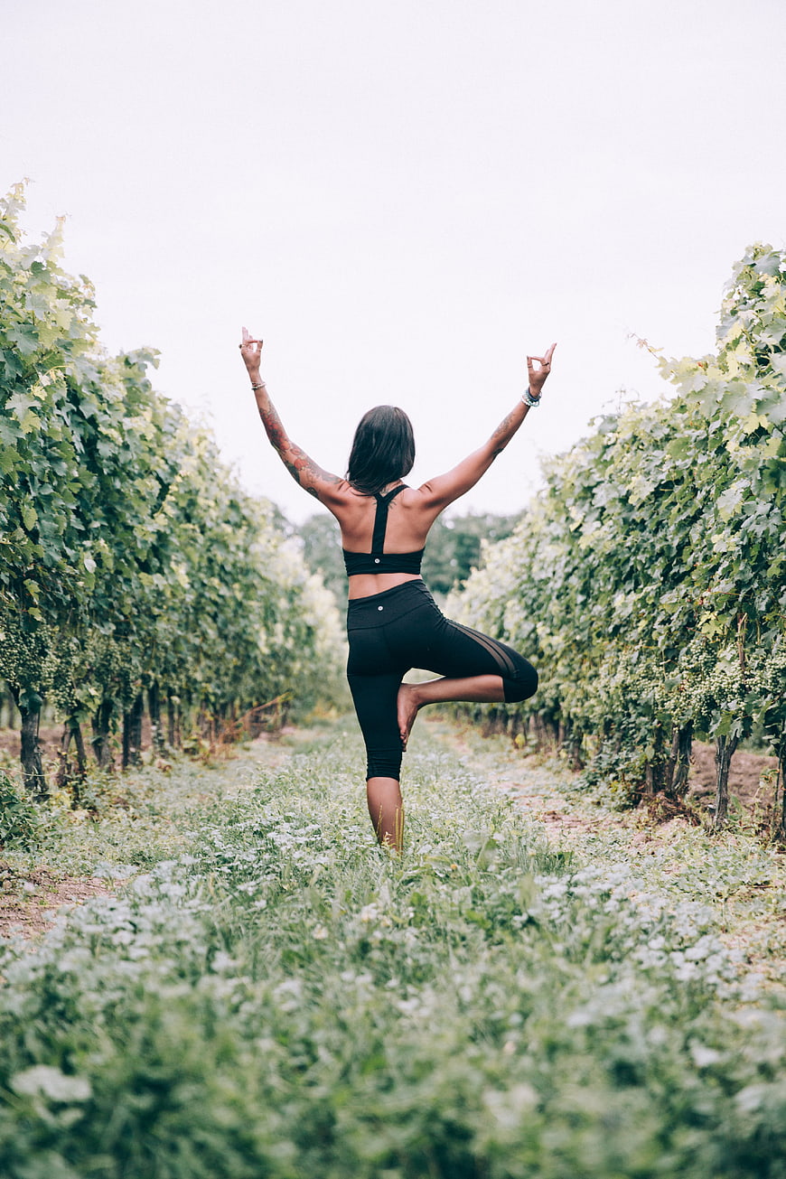 Woman doing yoga tree pose in vineyard
