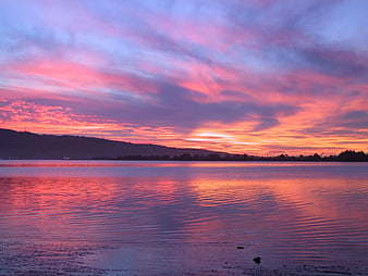 Vibrant Pink and Purple Sunset Over Calm Lake with Mountain Silhouette