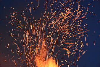 Dynamic burst of orange sparks against dark blue background