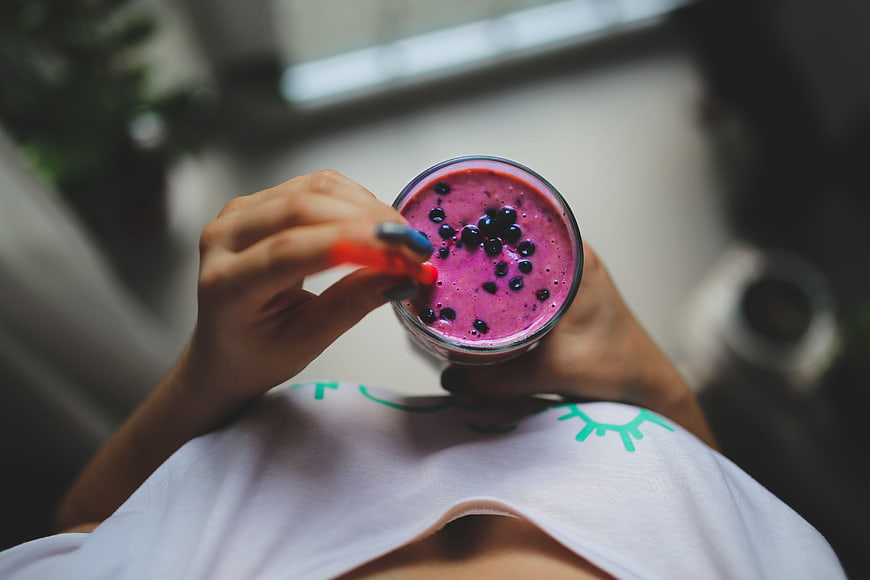 Top View of Woman Holding Berry Smoothie with Blueberries