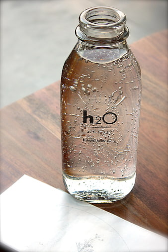 Glass water bottle with bubbles on wooden table