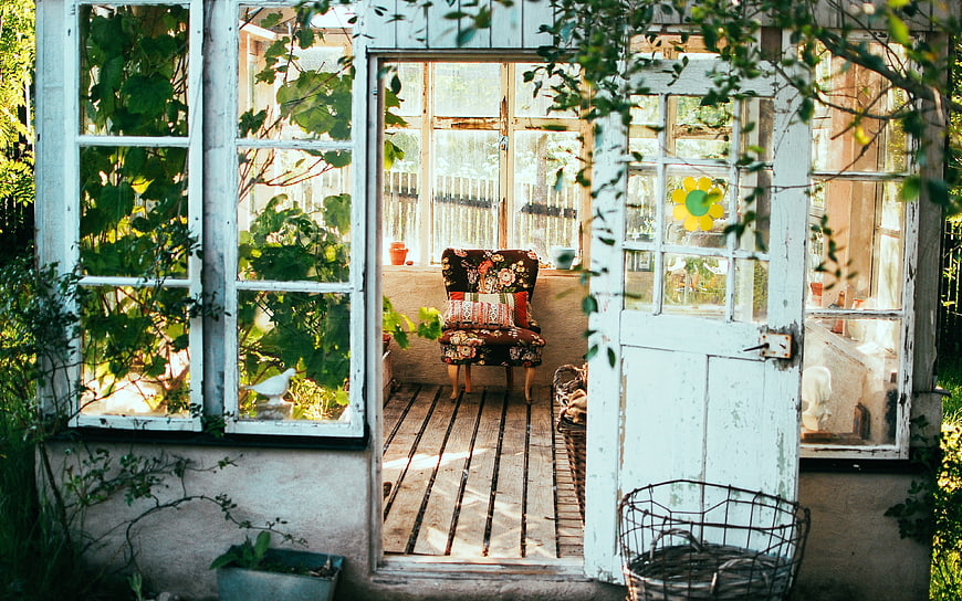 Vintage rustic sunroom with floral chair and garden view
