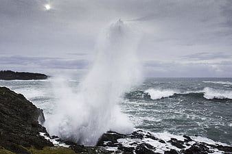 Powerful ocean wave crashing against rocky coastal cliffs