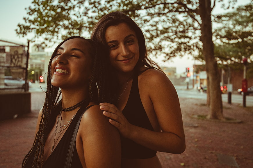 Two happy women laughing together on a city street