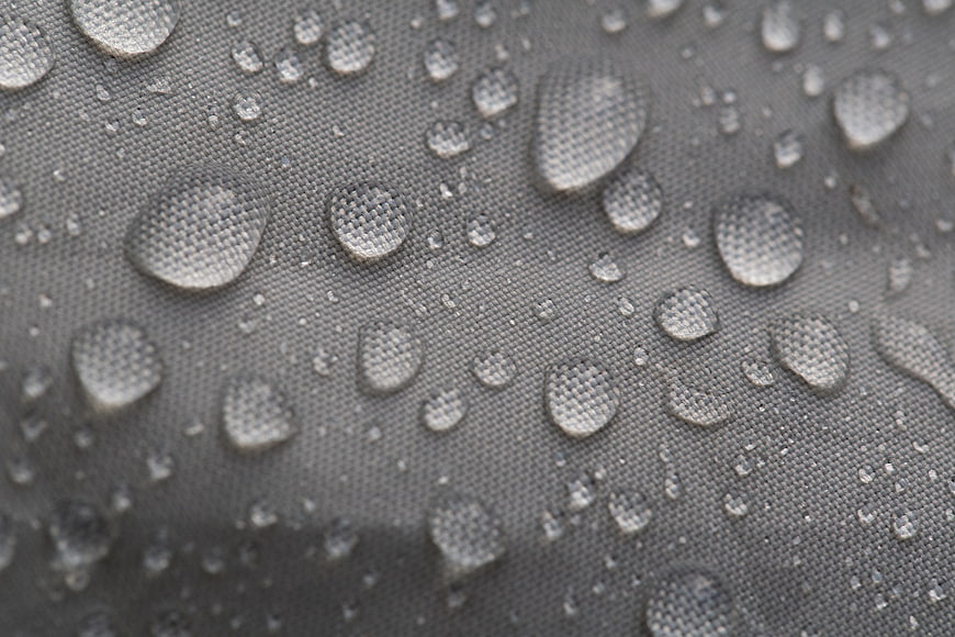 Macro shot of water droplets on gray waterproof fabric texture