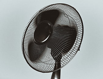 Black electric fan spinning against a gray background