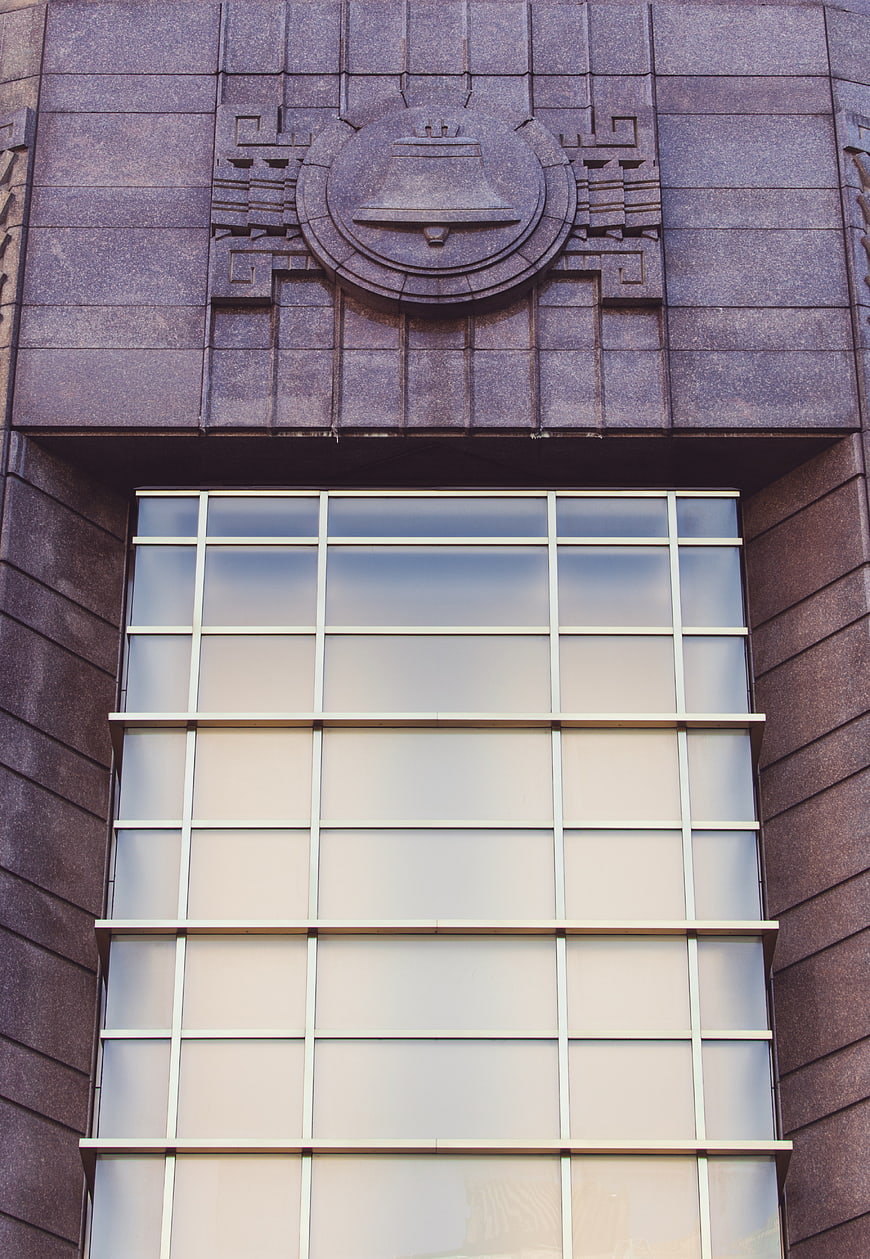 Art Deco stone facade with bell emblem and grid window