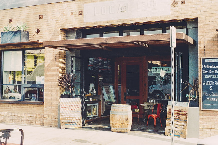 Exterior of Local 1205 Restaurant with Wooden Barrel and Menu Signs