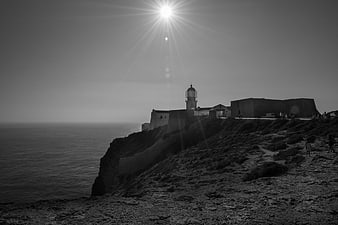 Black and white lighthouse on a rocky cliff overlooking the ocean
