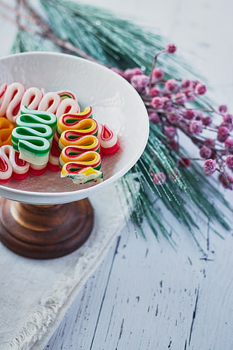 Colorful Christmas ribbon candies in a white bowl with pine branches