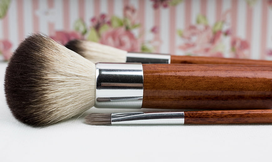 Close-up of wooden makeup brushes on white surface