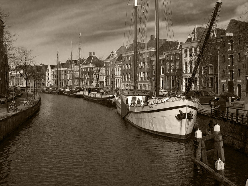 Vintage Sepia Canal Scene with Sailboats and Dutch Architecture