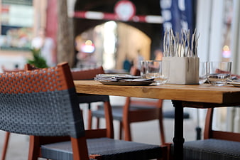 Set outdoor restaurant table with woven chairs and cutlery