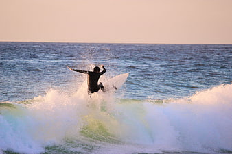Surfer riding a wave in the ocean at sunset