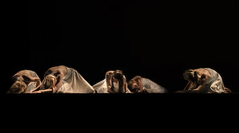 Group of female dancers in white dresses on dark stage