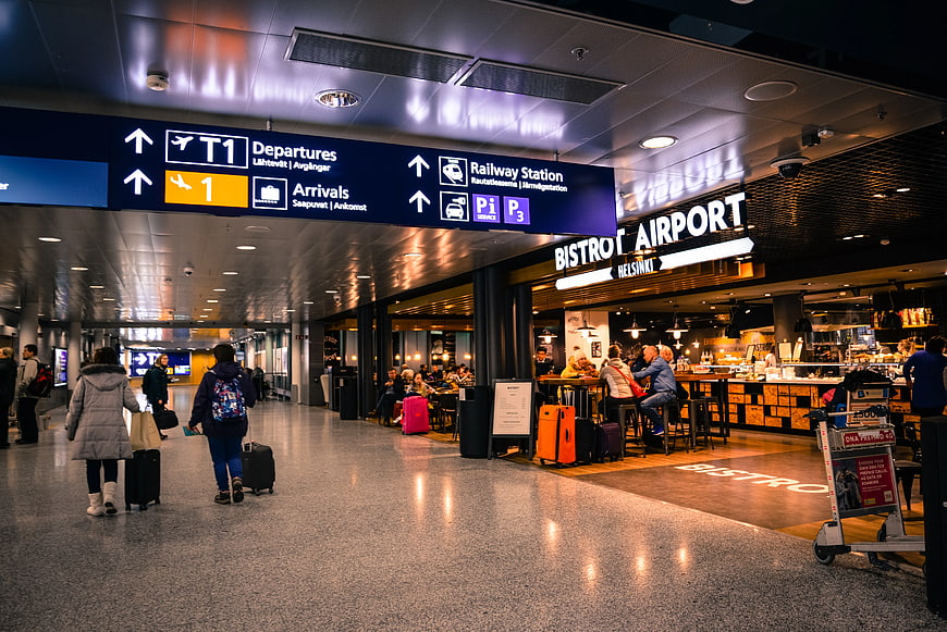 Travelers walking in Helsinki Airport terminal near bistro
