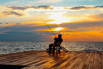 Silhouette of Man Fishing on Wooden Pier at Sunset