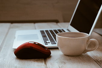 Red Mouse and Coffee Cup on Wooden Desk with Laptop