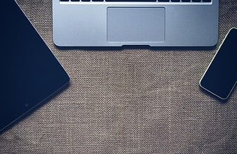 Flat lay of laptop, tablet, and smartphone on textured fabric