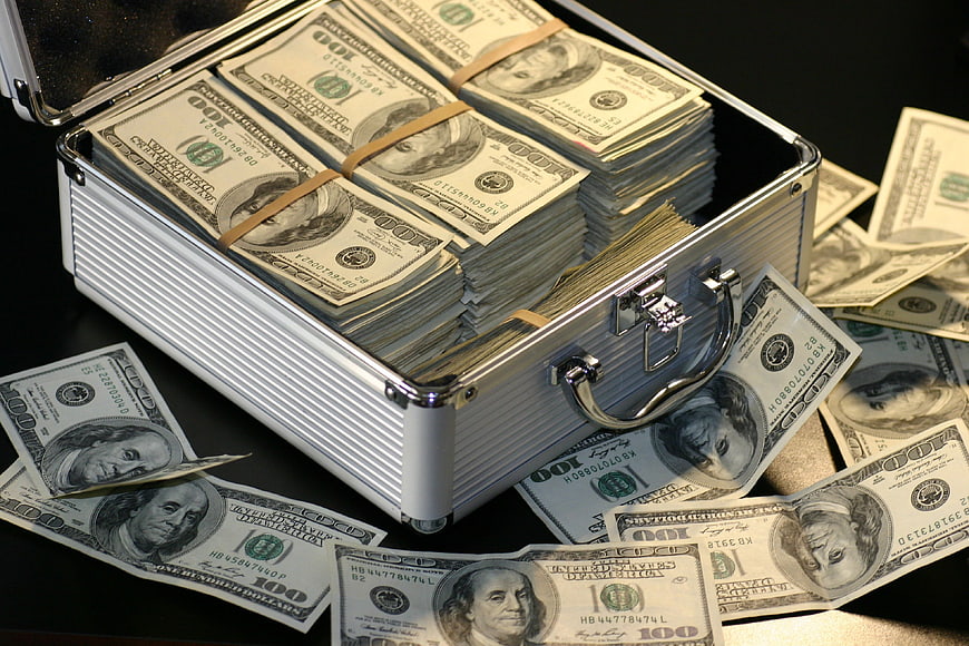 Open metal briefcase filled with stacks of hundred dollar bills