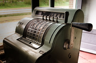 Vintage green mechanical cash register by window