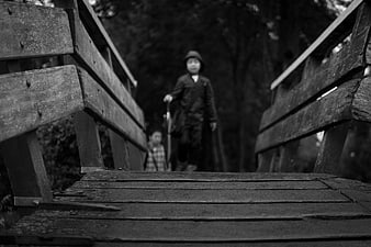 Black and white photo of children walking on a wooden bridge