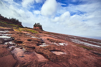 Red rocky coastline with tide pools and blue sky