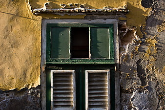 Weathered Green Wooden Window on Peeling Yellow Stucco Wall