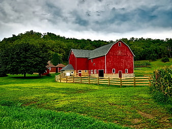 Classic Red Barn on Green Pasture with Stormy Sky
