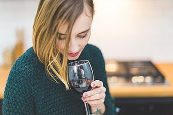 Woman smelling red wine in cozy kitchen