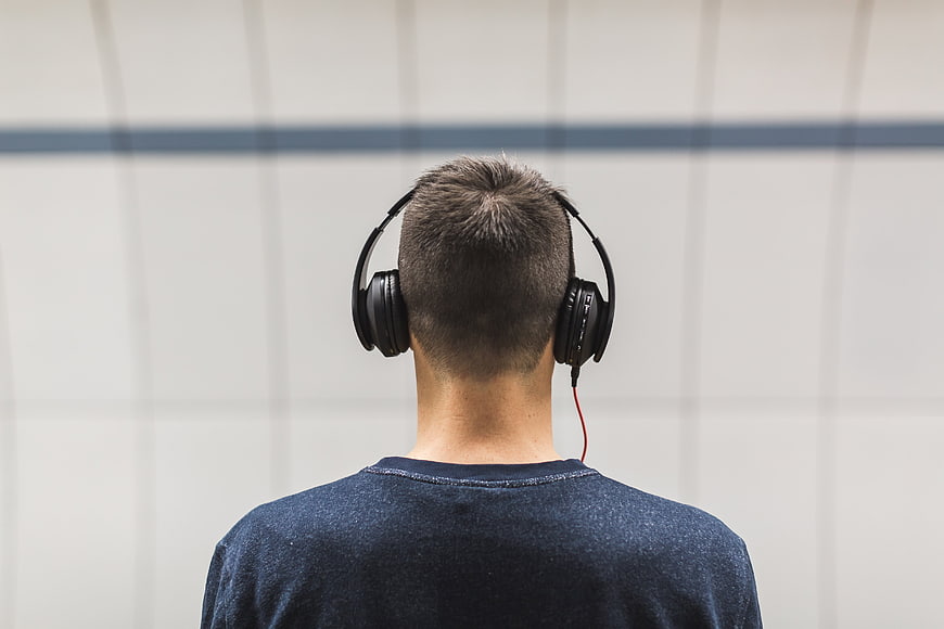 Back view of man wearing headphones listening to music