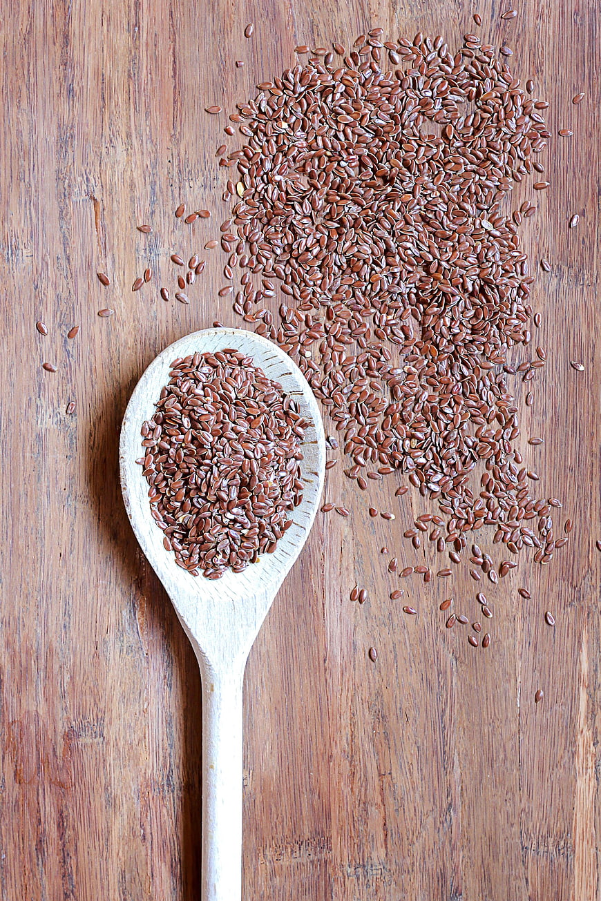 Brown flaxseeds on wooden spoon and rustic table background