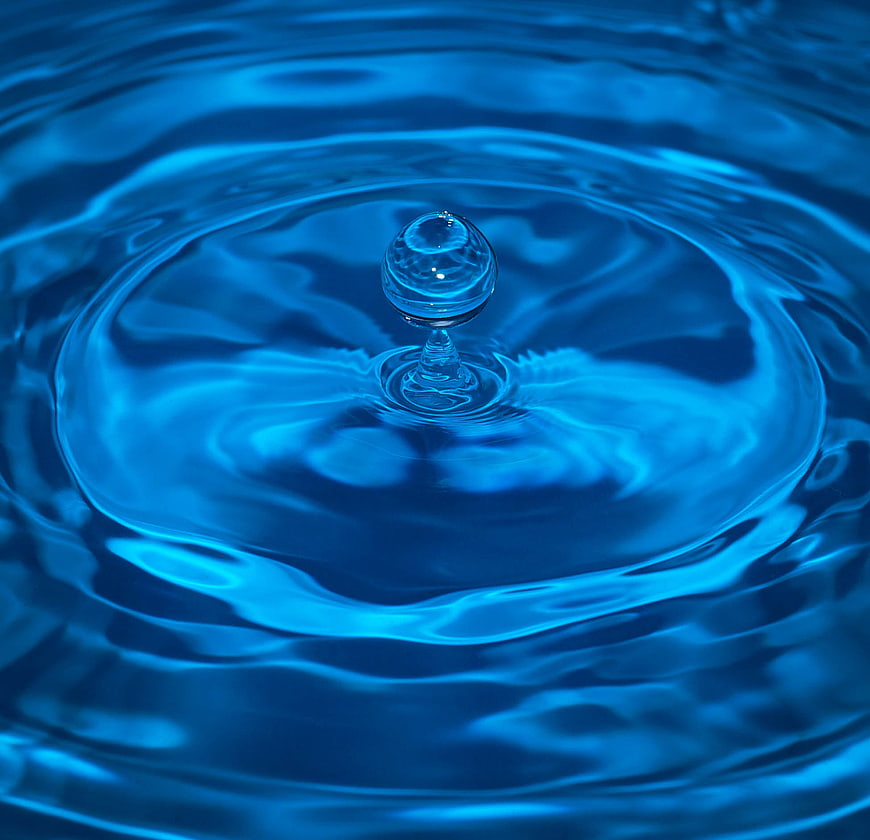 Macro shot of a blue water droplet creating ripples