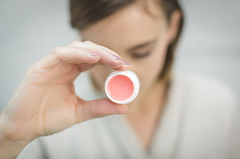 Woman holding pink lip balm close-up