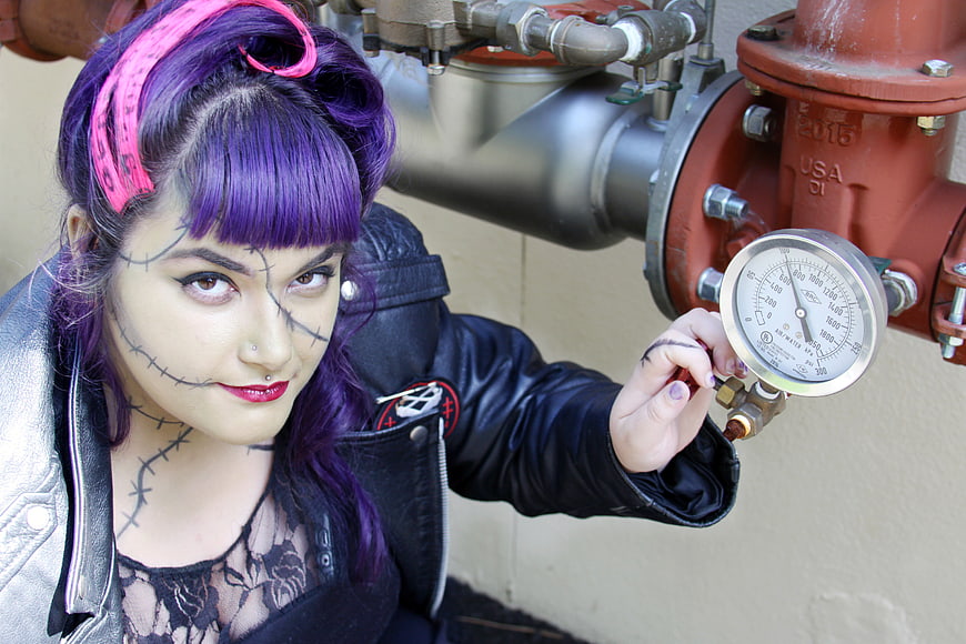 Gothic woman with purple hair checking pressure gauge