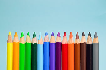 Row of colorful pencils on light blue background